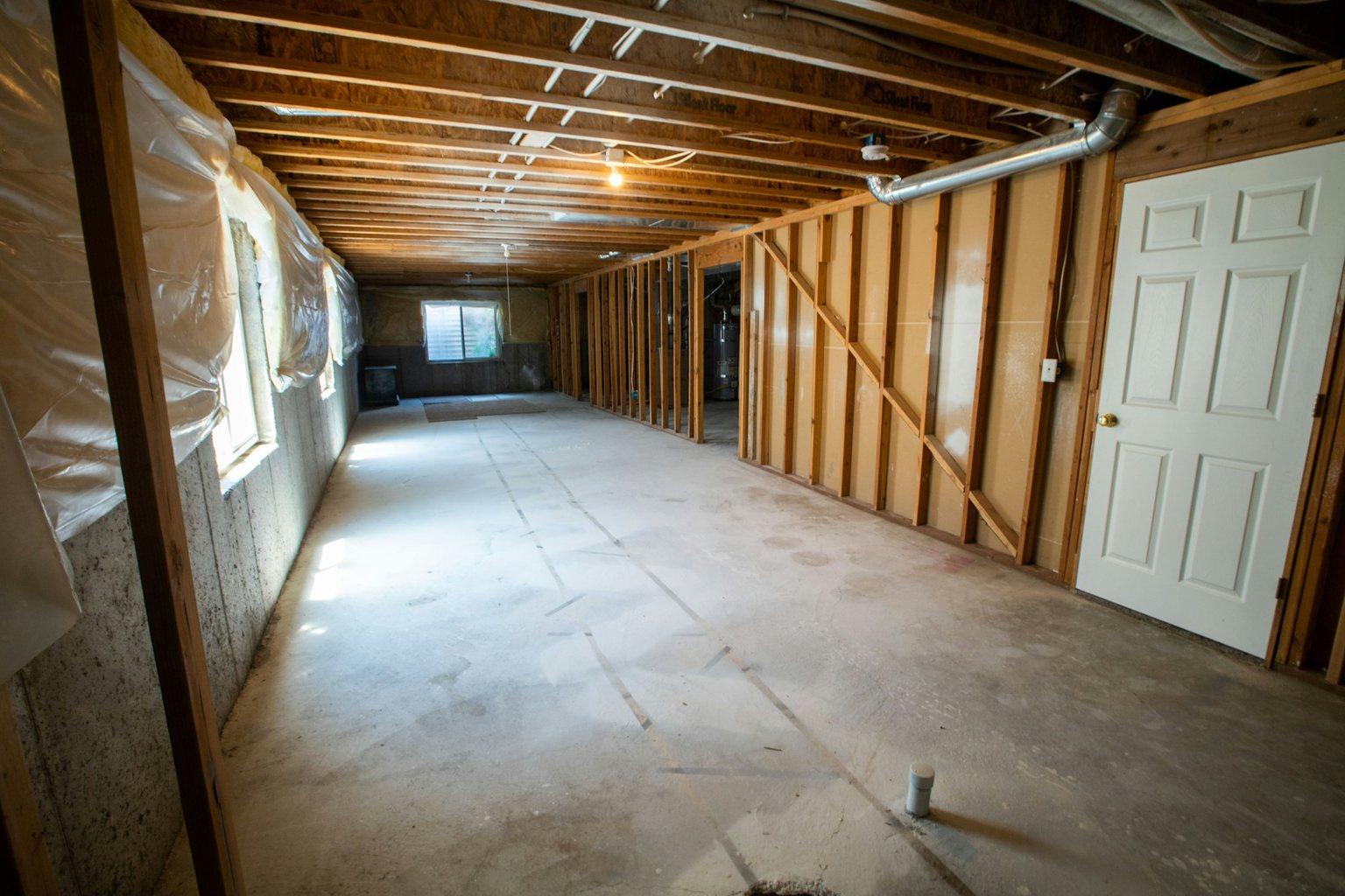 Unfinished basement with wood framing, exposed joists and a concrete slab