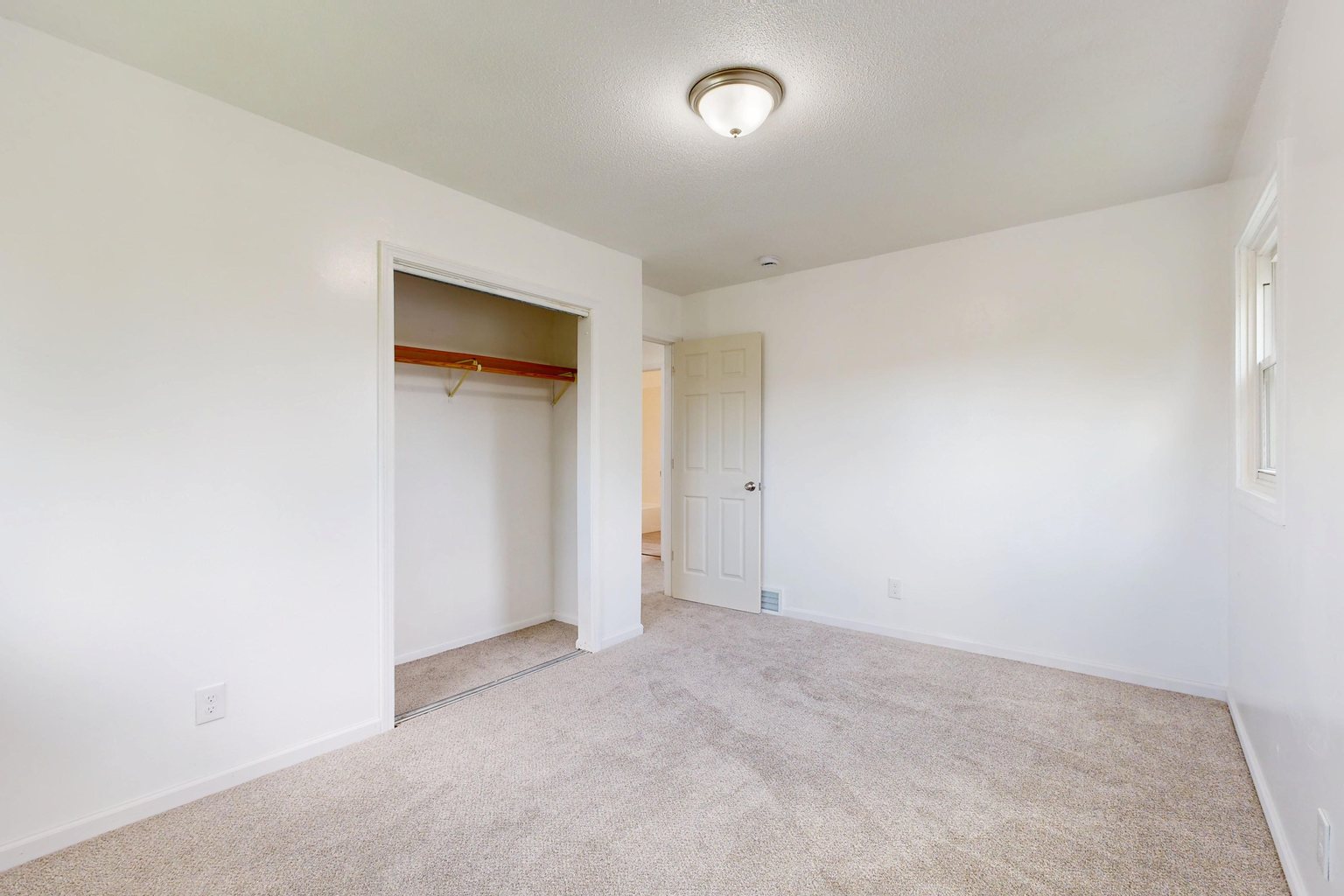 Empty bedroom with beige carpet and a closet