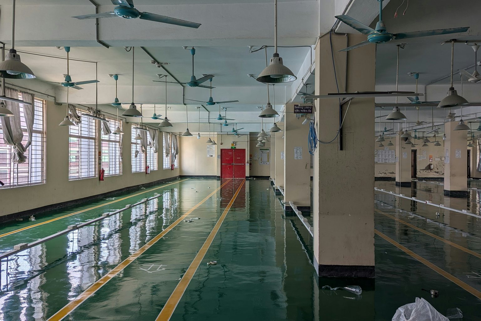 Factory interior with a reflective green floor and yellow walkway markings