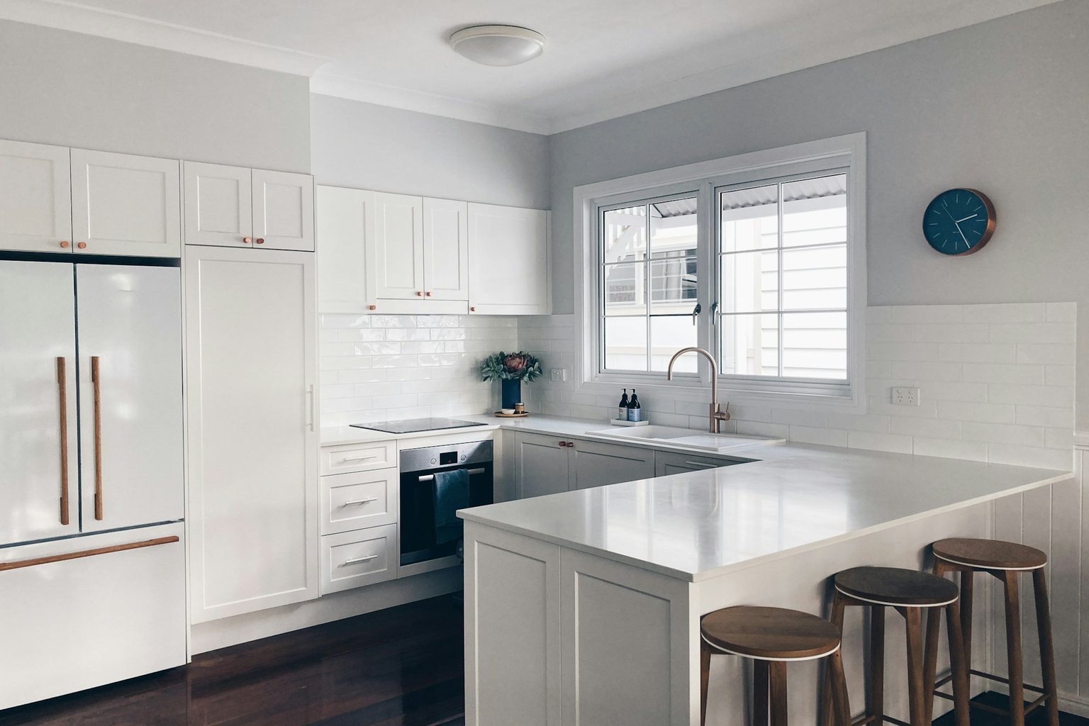 White kitchen with a peninsula, wood stools and subway tile backsplash