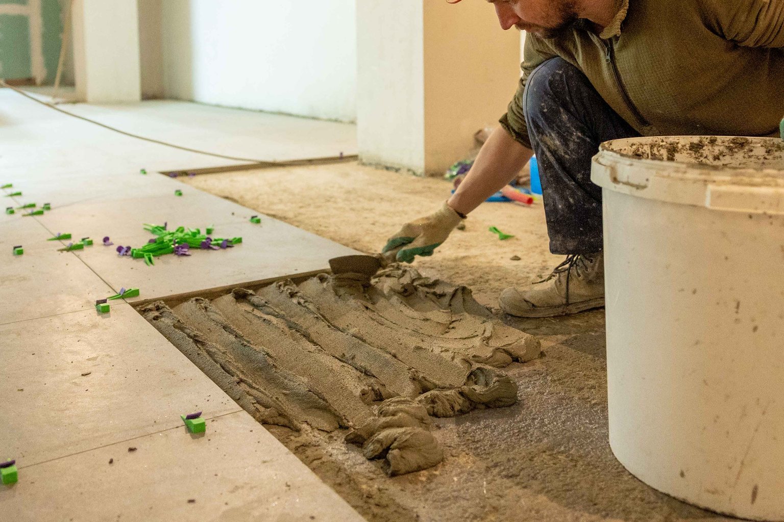 Installer spreading mortar and placing large floor tiles