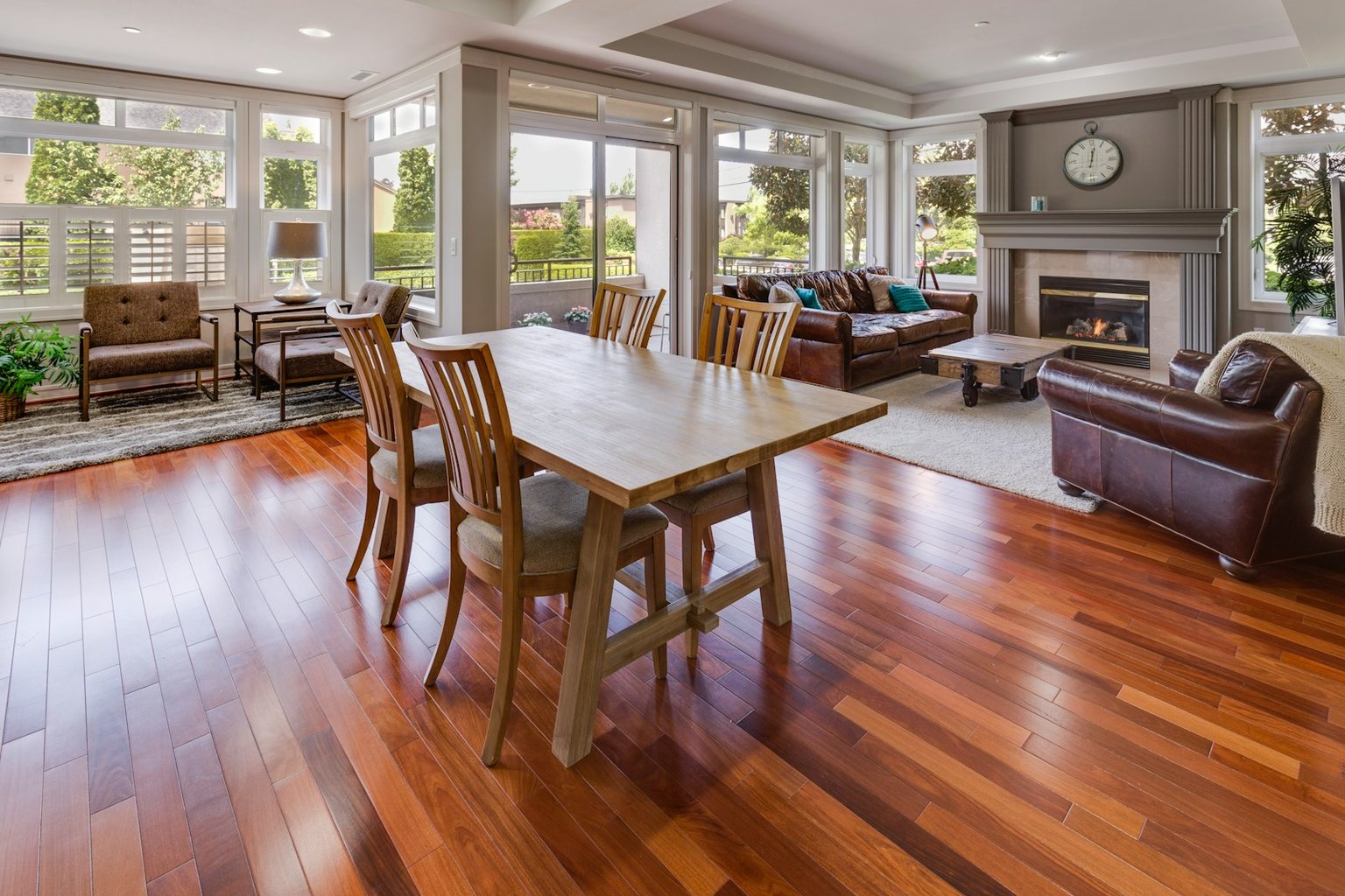 Open living and dining room with warm wood flooring and large windows