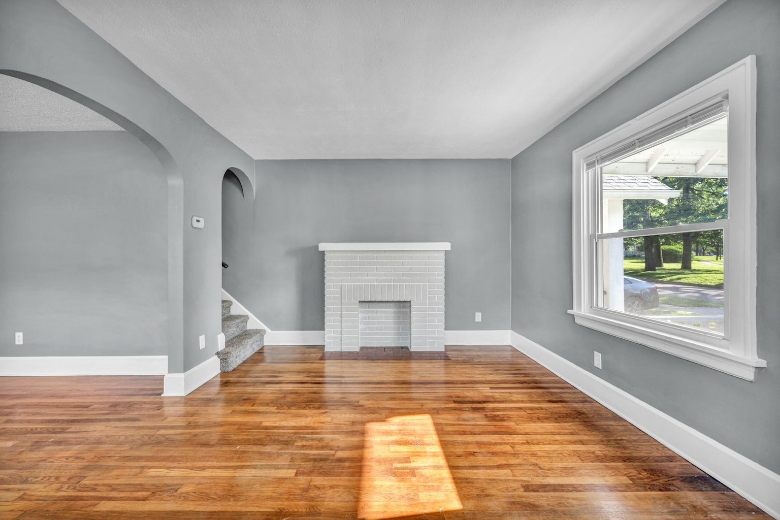 Unfurnished living room with a fireplace, bay window and wood flooring
