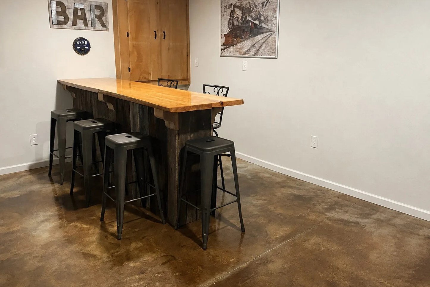 Mottled brown and amber acid-stained concrete floor beneath a residential basement bar.