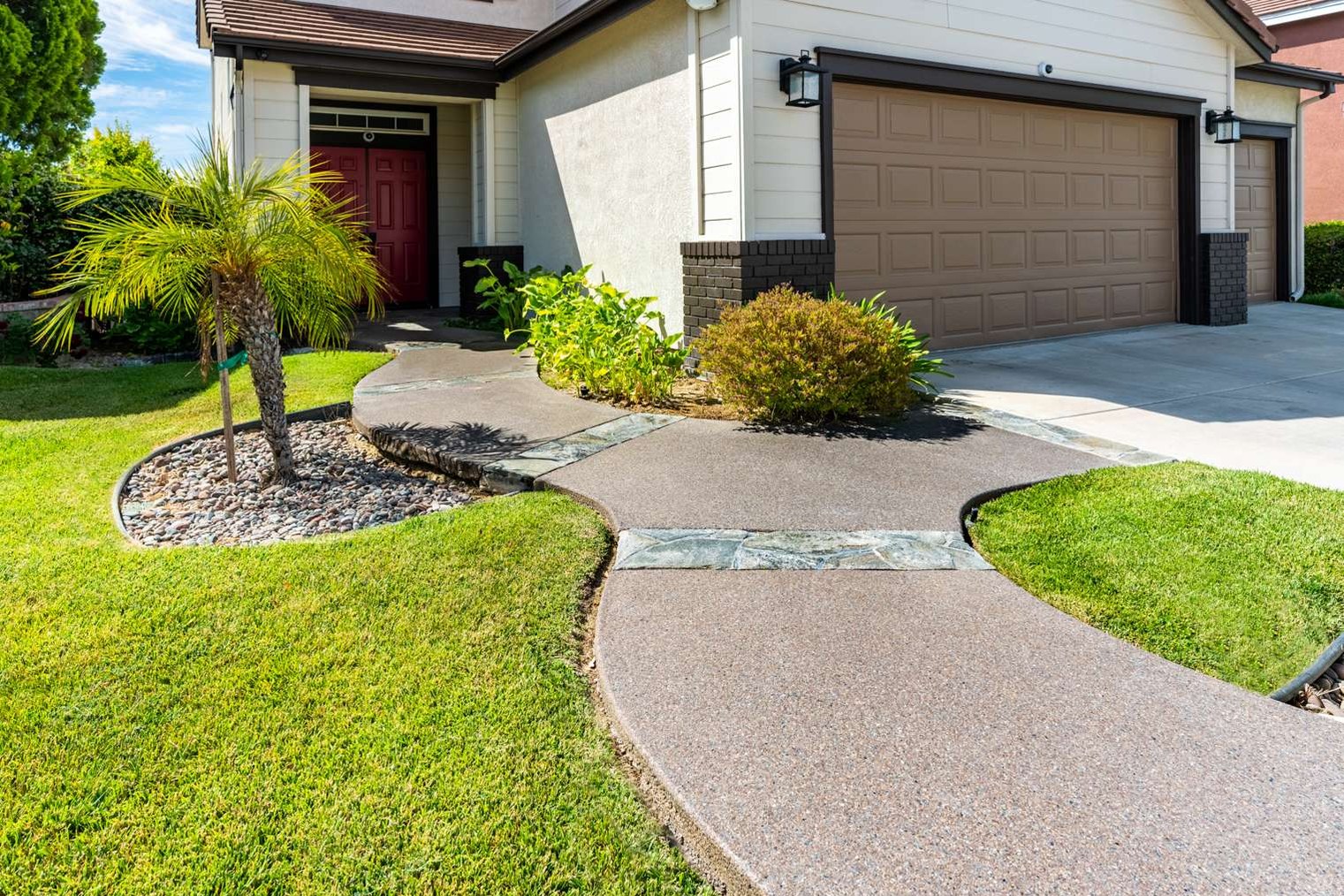 Speckled coated concrete walkway and shallow entry steps leading to a red front door.