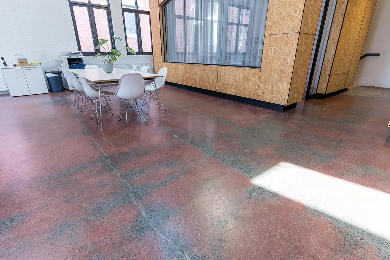 Matte grind-and-seal concrete office floor with exposed aggregate and natural reddish-gray variation.