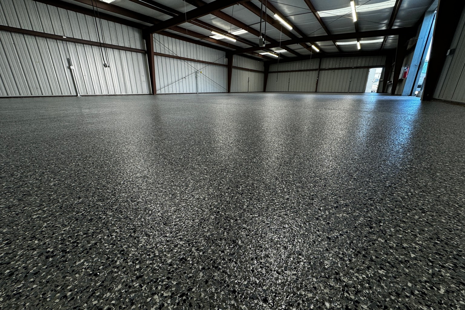Industrial warehouse with exposed steel framing and a continuous gray full-flake floor coating.