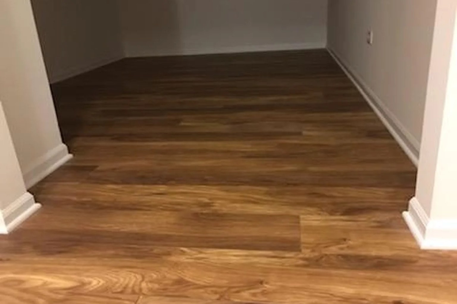 Warm wood-grain laminate flooring through the entrance to a finished bedroom.