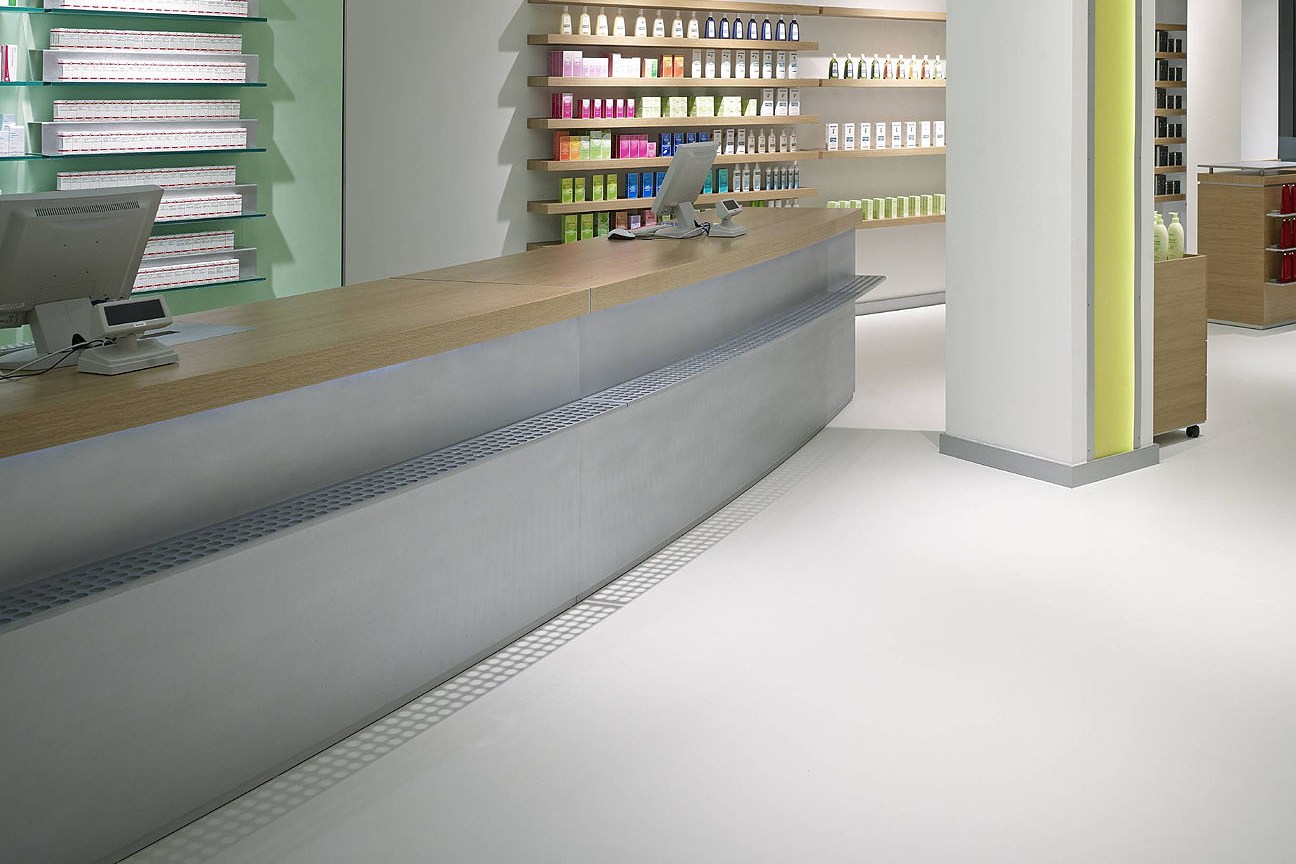 Seamless white resin floor beneath the counter and medicine shelves in a pharmacy.