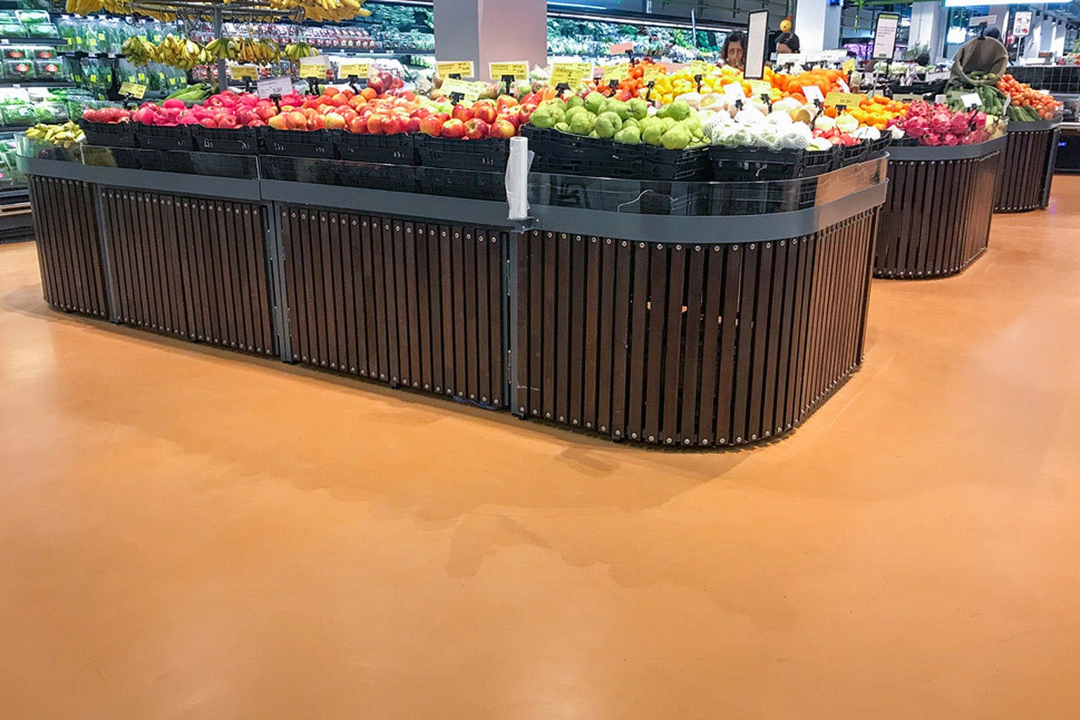 Grocery produce displays surrounded by a seamless warm clay colored resin floor.