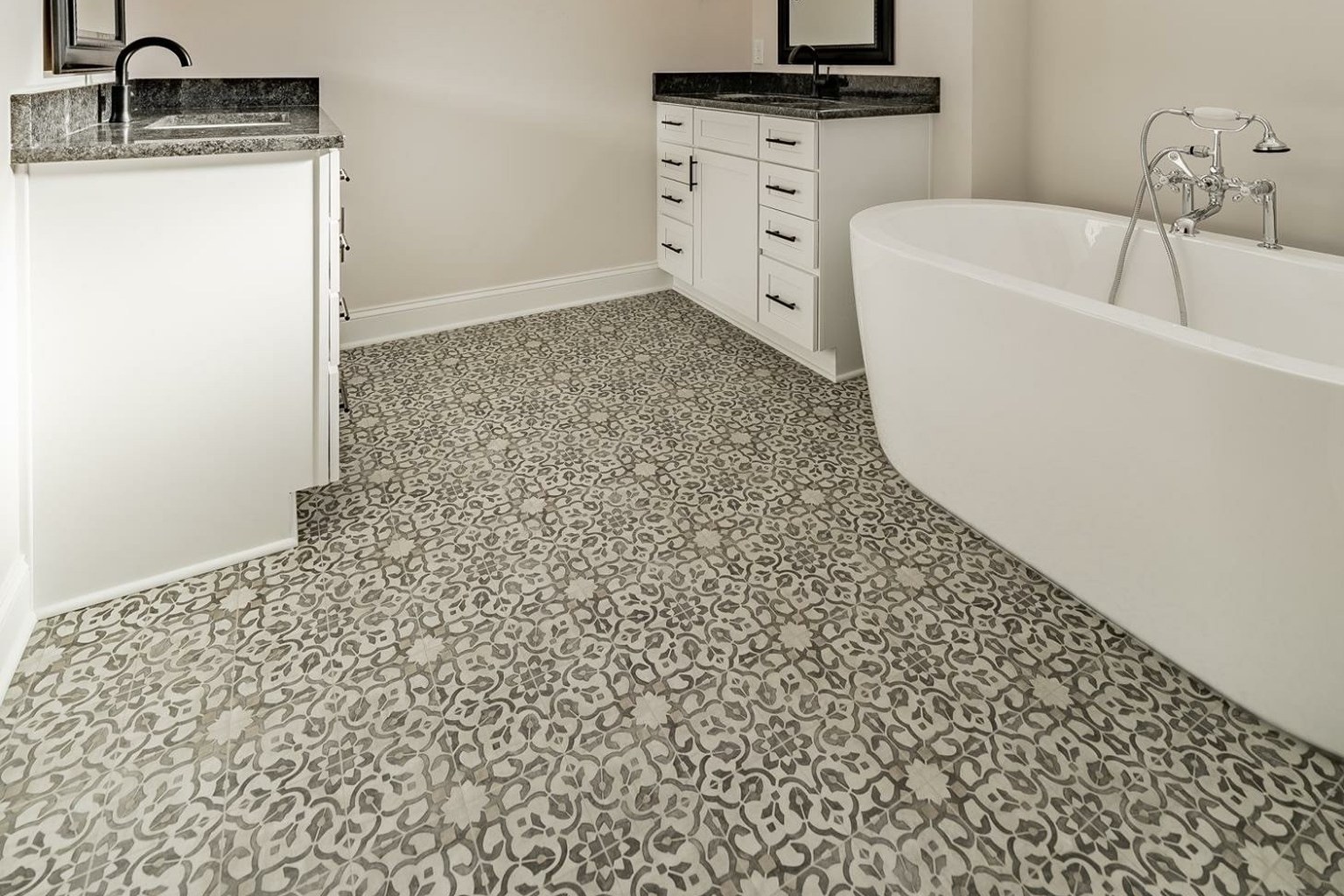 Patterned sheet vinyl flooring beneath a freestanding tub and white bathroom vanities.