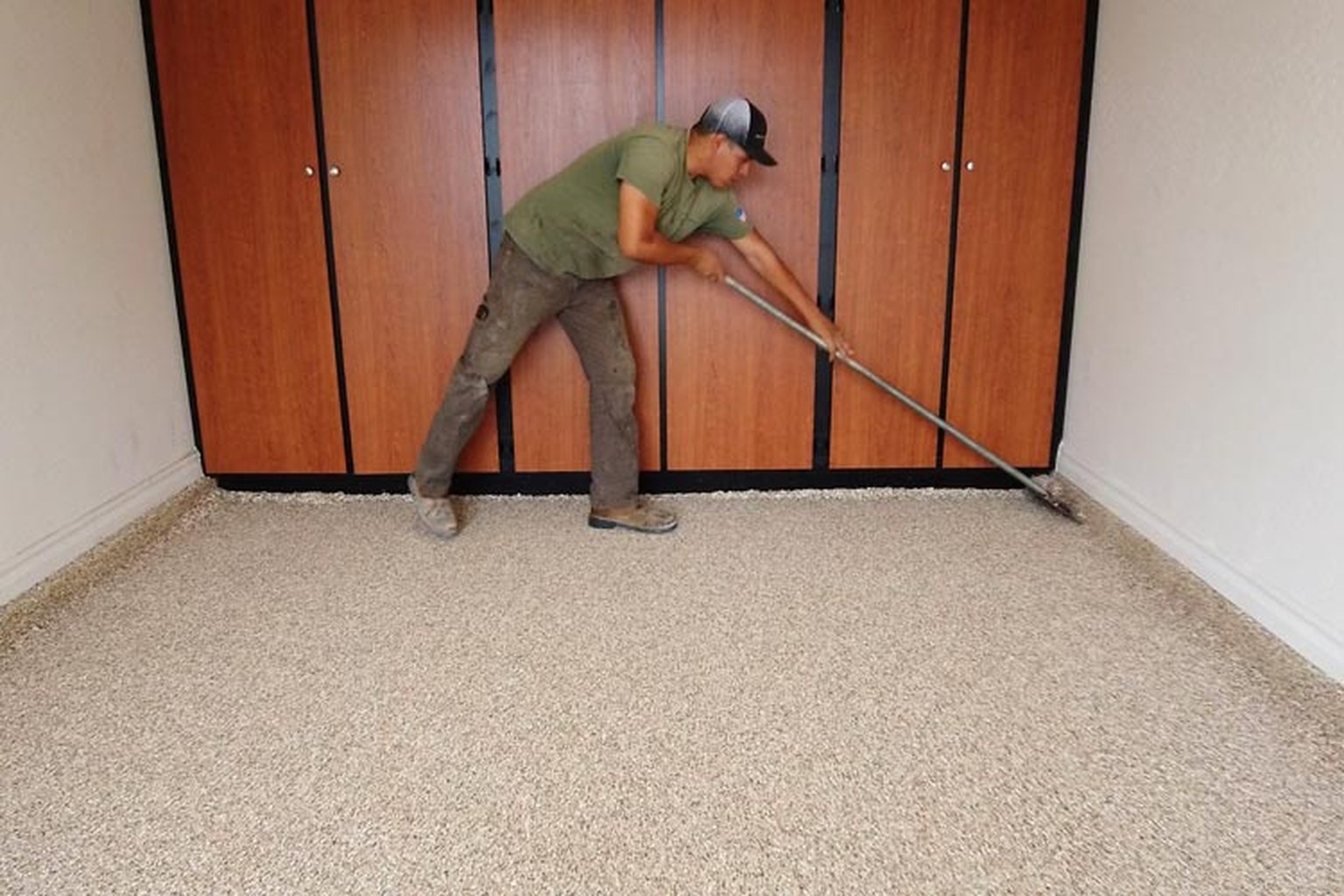 Installer scraping loose decorative flakes from a cured garage-floor coating.